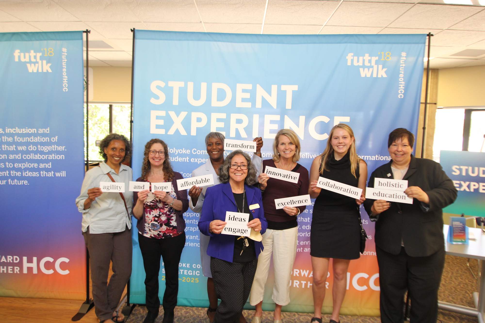 HCC President Christina Royal poses with community members at the Future Walk event. They are each holding an inspirational word printed on a large piece of paper. Words include "agility," "hope," "affordable," "innovative," and "collaboration."